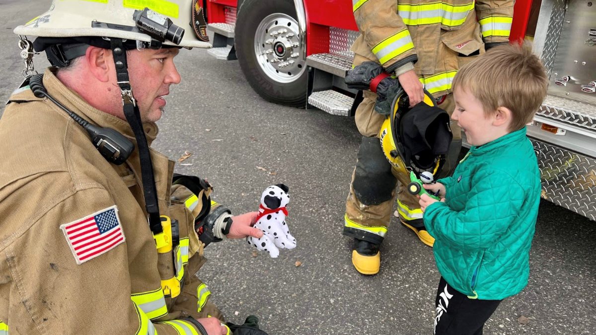 A Teton Village Special Fire District fireman shows a toy Dalmatian to a child.