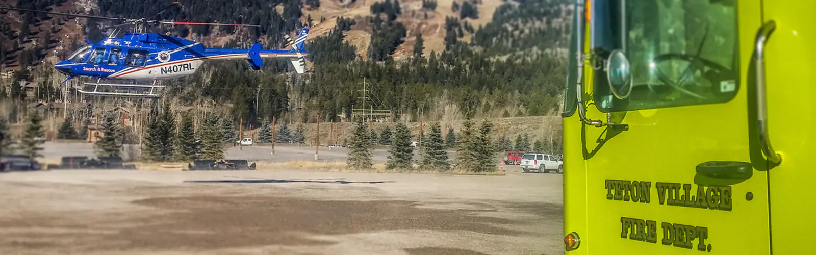 A search and rescue helicopter landing near a fire truck in Teton Village, WY.
