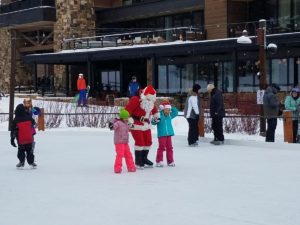 Santa skates with two children on the Village Rink on the Commons in Teton Village, WY.